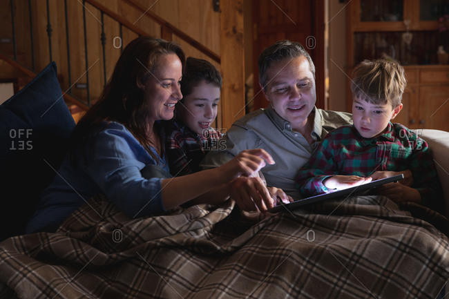 Front view close up of a middle aged Caucasian man and woman using a tablet computer with their two pre teen sons at home