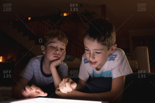 Front view close up of two pre teen Caucasian boys using a tablet computer in a sitting room