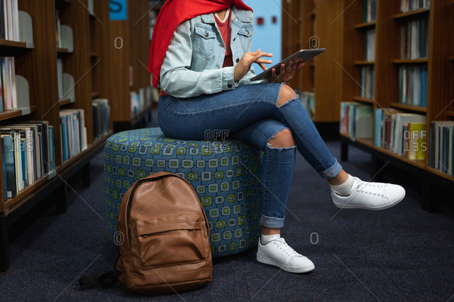 Side view low section of a young Asian female student using a tablet computer and studying in a library
