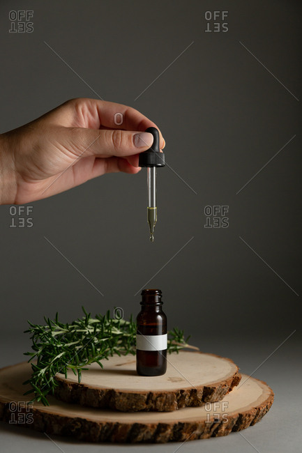 Hand holding dropper dripping with essential oil