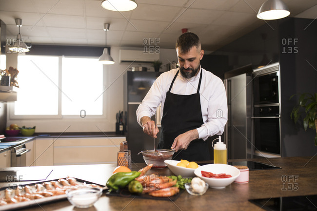 Bearded chef preparing sauce in kitchen