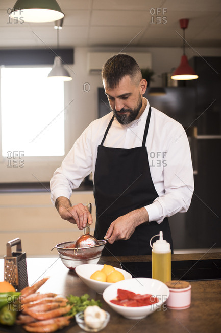 Bearded chef preparing sauce in kitchen