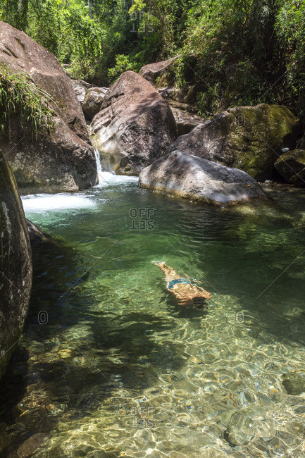 Man enjoying beautiful green rainforest river with crystal clear water