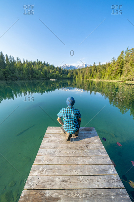Rear view of man on pier looking at crestasee lake, switzerland