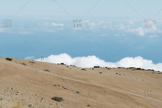 Minimalistic image of empty trail against blue sky over clouds