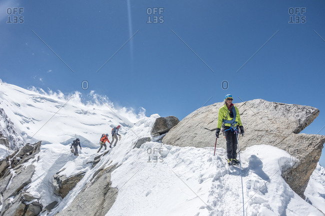 France, Auvergne-Rhone-Alpes, Chamonix - June 13, 2019: A senior climber walks across a ridge with a rope team in the back