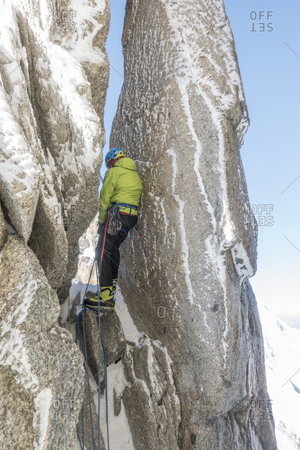 Alpinist navigates a chimney between 2 grime crusted mt blanc spires