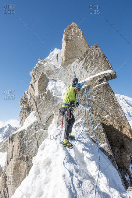 Alpinist manages his ropes after completing a short rappel