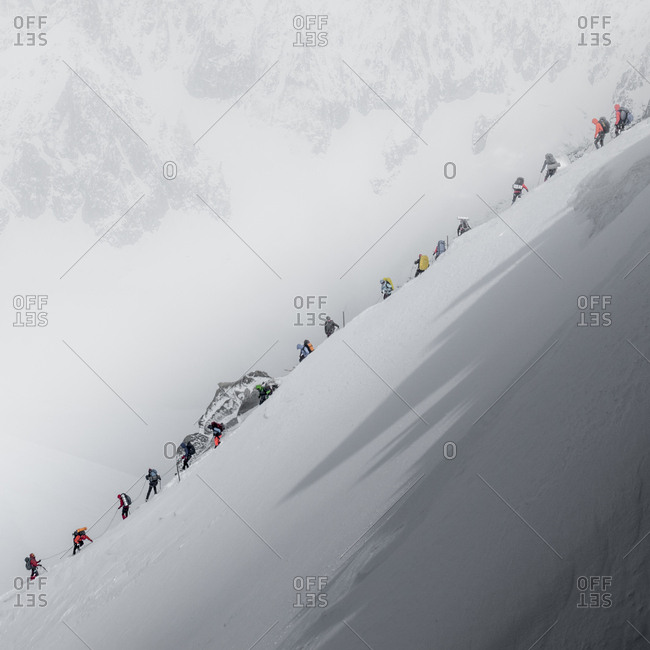 Traffic jam on mt blanc as a string of climbers navigate a steep ridge