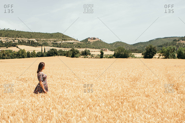 Quiet young woman with floral dress looking away in a rural scenery