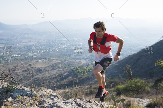 Male trail runner navigating rocky terrain as he climbs the arid mountains near el arenal, hidalgo, mexico.