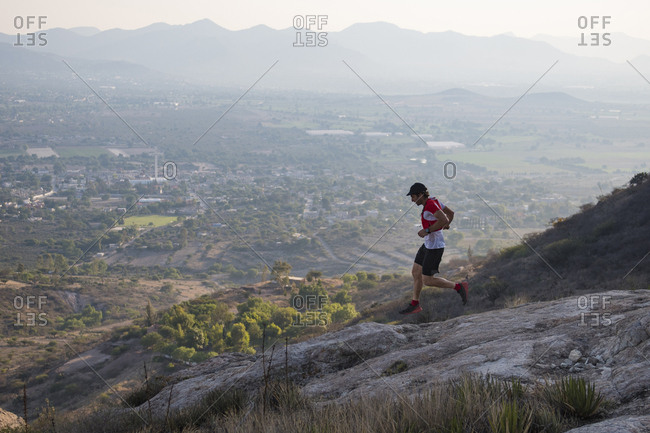 Athletic male trail runner flying down rocky terrain in the arid mountains of el arenal, hidalgo, mexico