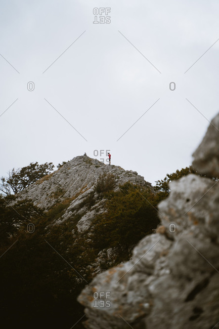 Lonely hiker meditating before reaching the top of a mountain on a foggy day