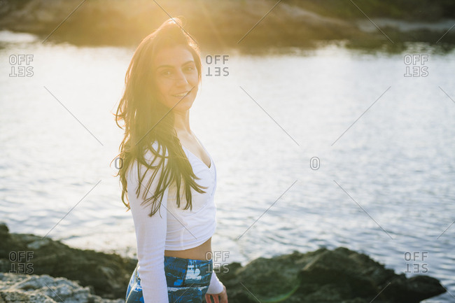 Candid moment of young woman doing yoga on the rocks at golden hour