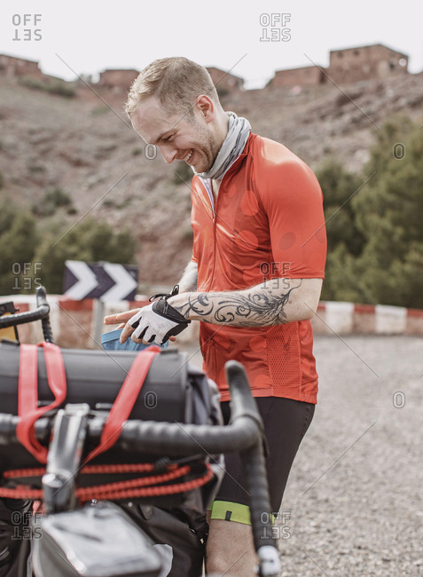 Morocco, Marrakesh-Safi, Asni - April 2, 2019: A young man smiles while packing up his bike in morocco