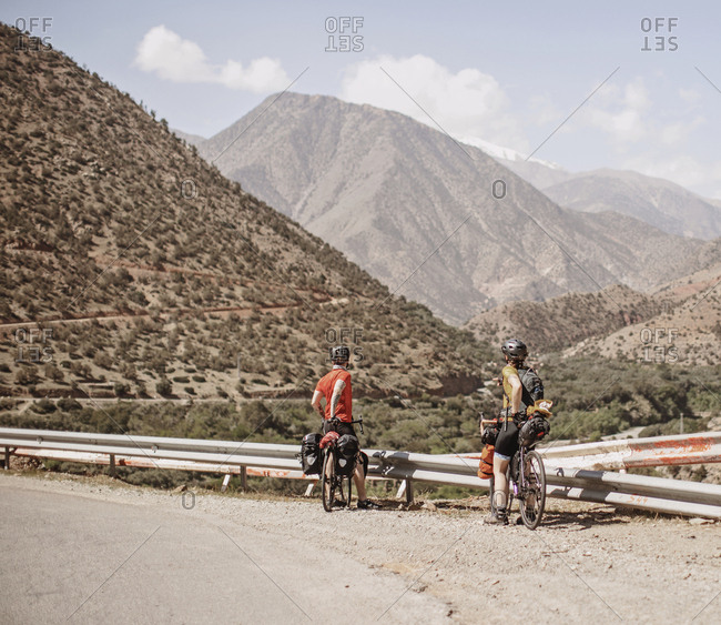 Morocco, Souss-Massa - April 3, 2019: A couple of cyclists look at the view of the atlas mountains, morocco
