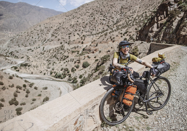Morocco, Souss-Massa - April 3, 2019: Female cyclist smiles while bikepacking in the atlas mountains morocco