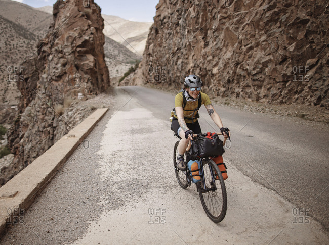 Atlas Mountains, Morocco - April 3, 2019: A female bike packer rides along a mountain road in the atlas mountain
