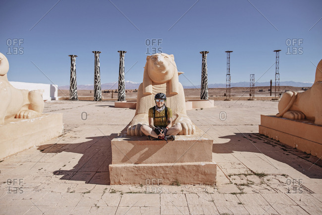 Morocco, Draa-Tafilalet, Ouarzazate - April 8, 2019: A female cyclist sits in an old movie set, ouarzazate, morocco