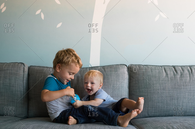 Two little boys playfully wrestling over a sippy cup
