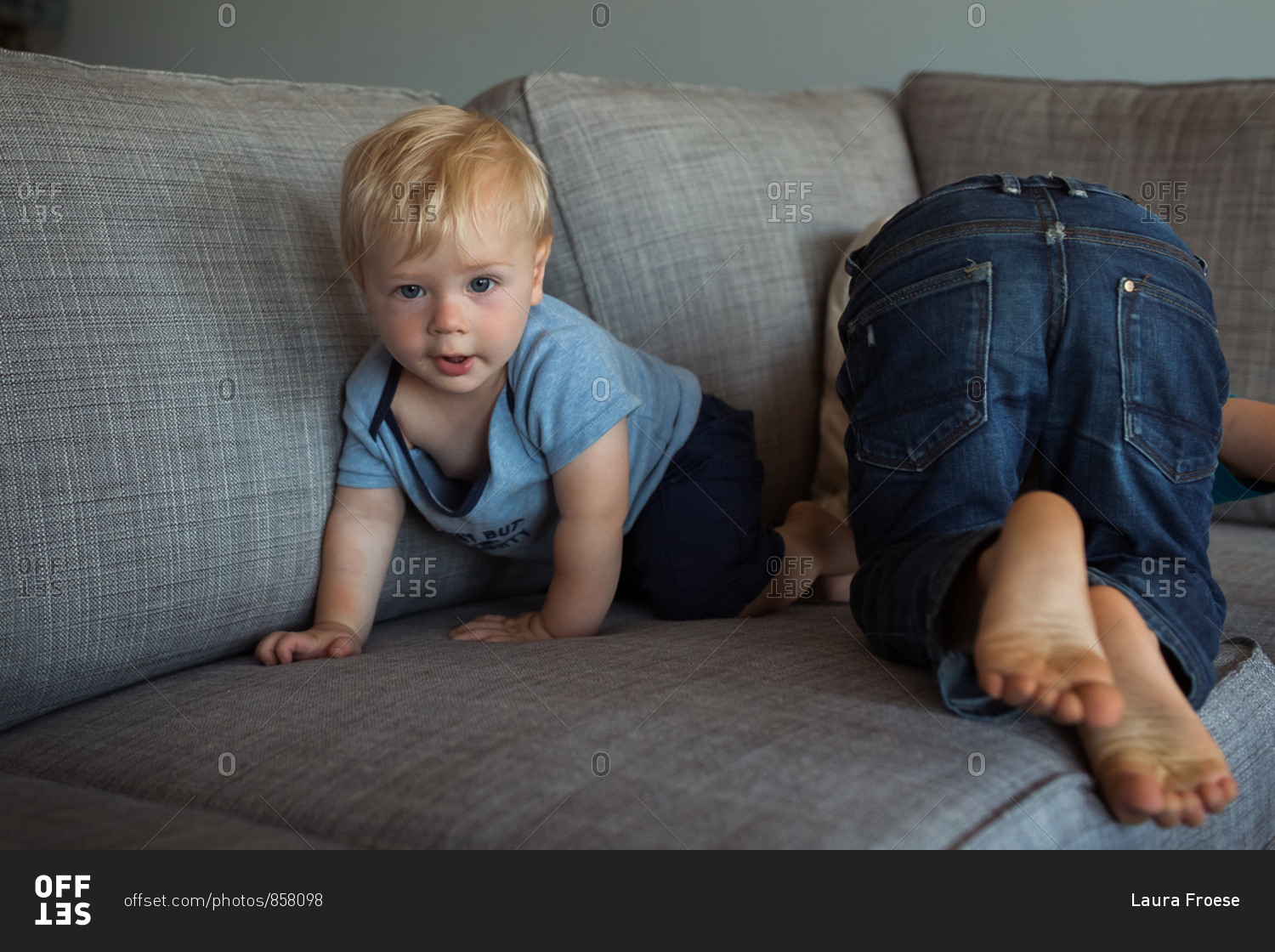 Two toddler boys playfully wrestling on a sofa