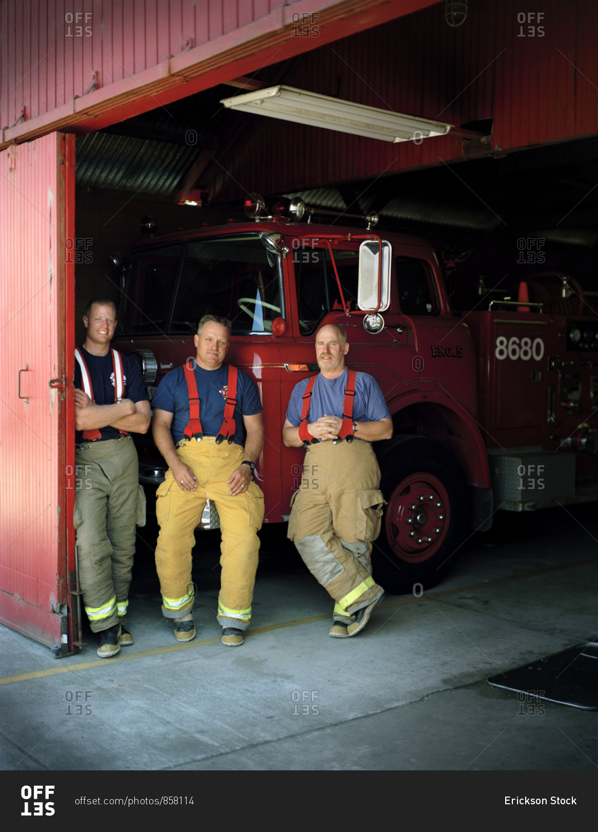 Three firemen back resting on a fire truck.
