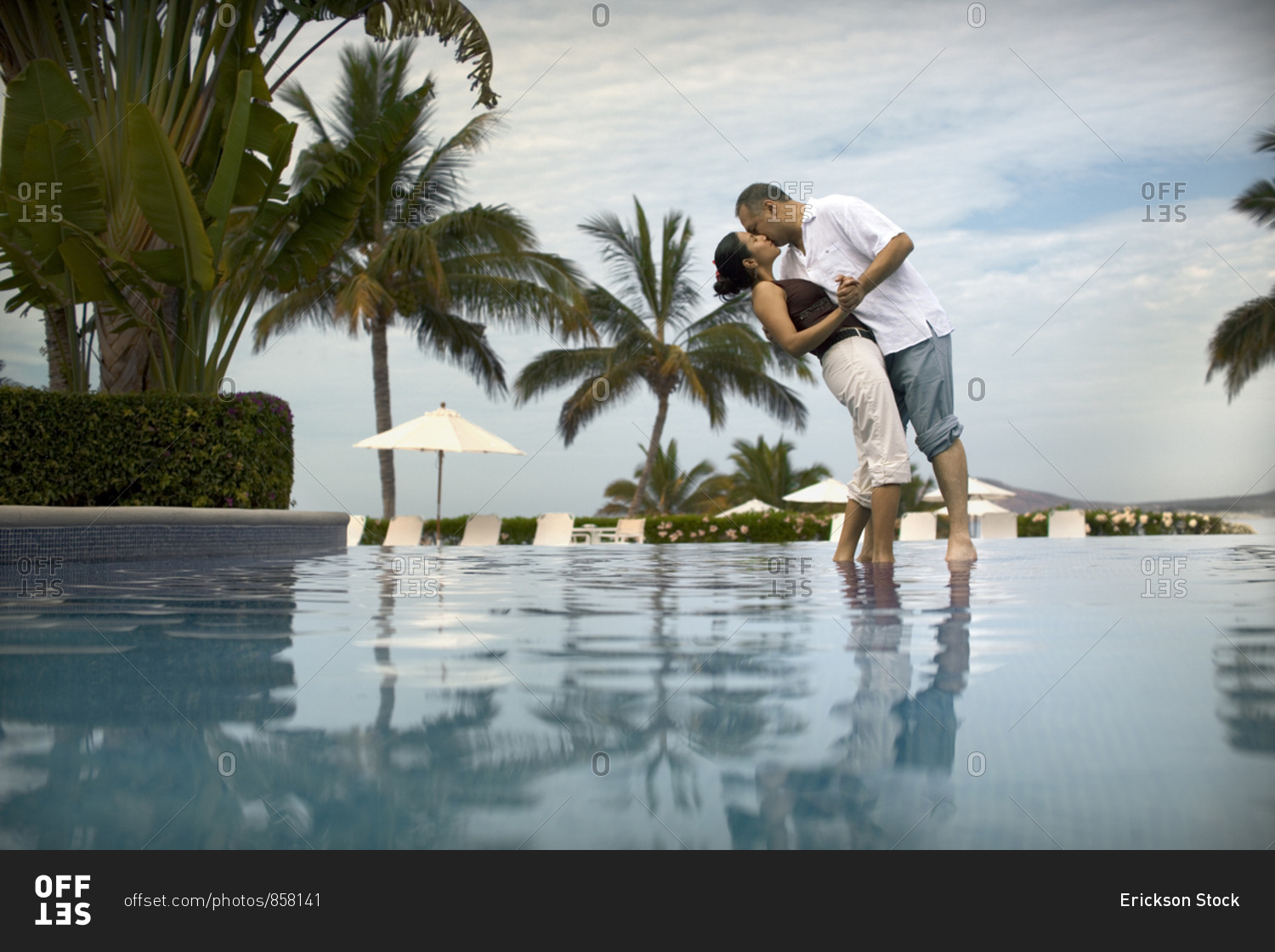 A man smooches his soul mate near the swimming pool.