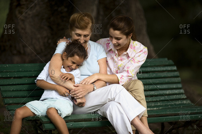 A family seen seated together on a bench.