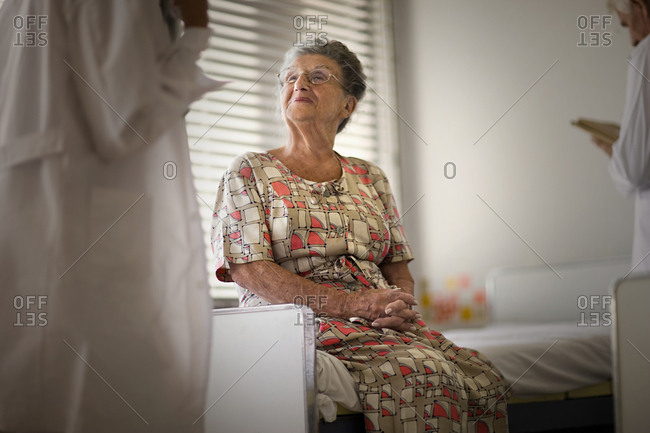 View of a woman sitting on the bed as doctors involved in work.