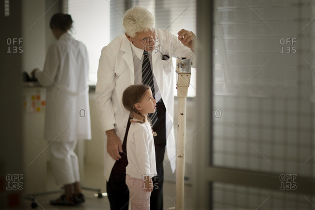 View of a doctor checking a girl����䋢s weight.