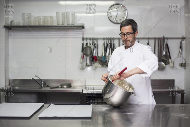 Chef kneading dough in bowl working in modern kitchen