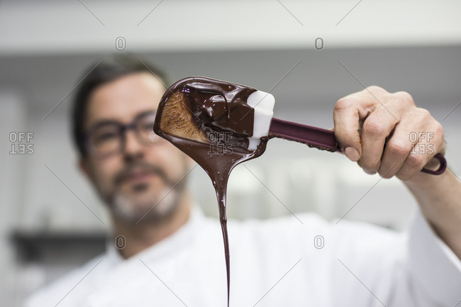 Chef looking at chocolate cream in a spatula