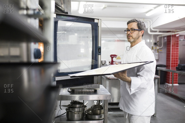 Man placing cooking tray in oven
