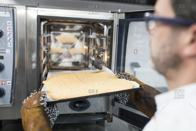 Man placing cooking tray in oven