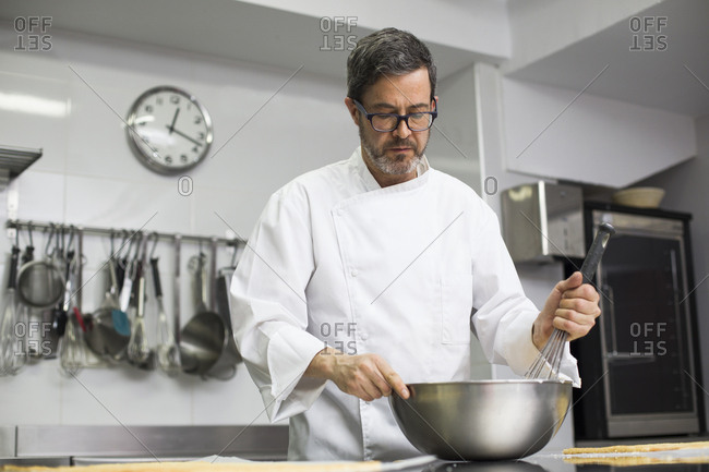 Chef in kitchen mixing cream in bowl