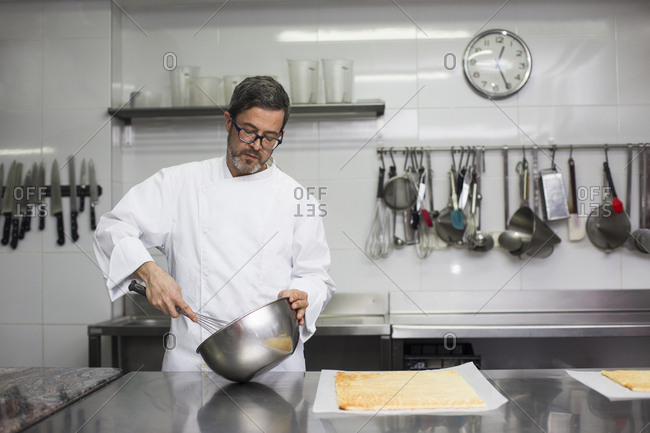 Chef in kitchen mixing cream in bowl
