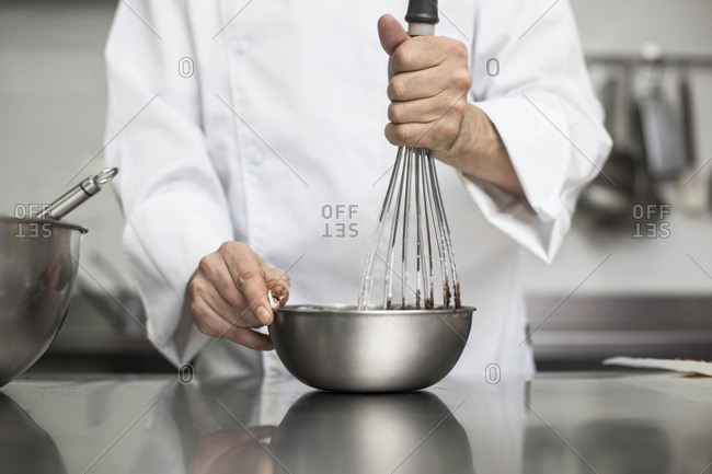 Chef whipping cream with whisk in bowl