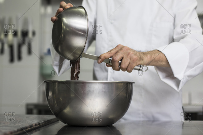 Chef pouring chocolate mass into mixing bowl