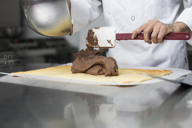 Chef placing chocolate cream on cake layer