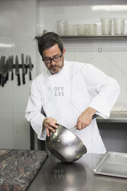 Chef in kitchen mixing cream in bowl