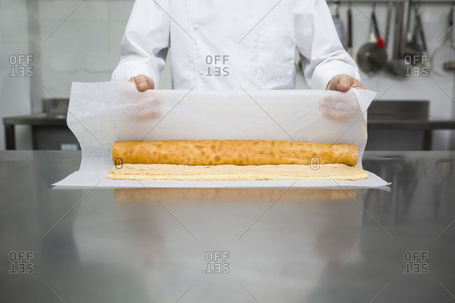 Chef preparing pastry roll with baking paper