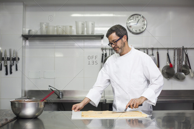 Concentrated chef spreading cream on biscuit layer