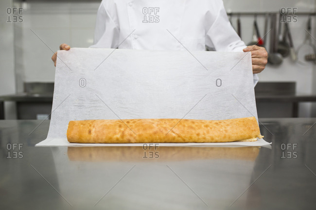 Chef preparing pastry roll with baking paper