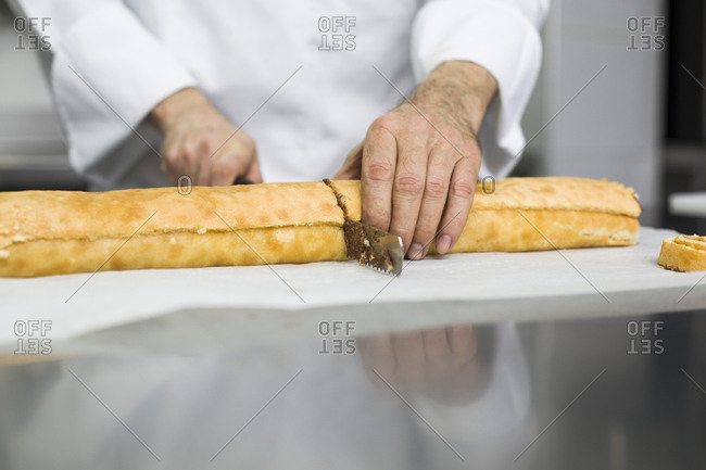 Chef cutting cake roll in portions
