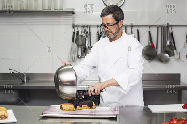 Chef pouring chocolate on rolled cake