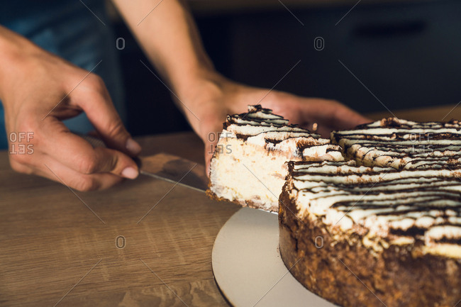 Women's hands hold the piece of cut cake on knife. Close up