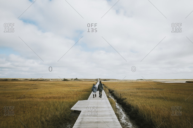 Two boys walking on boardwalk across salt marsh