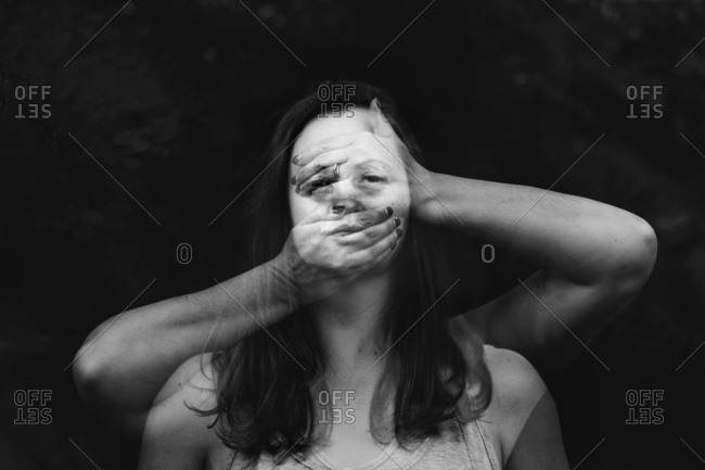 Black and white double exposure portrait of female behind hands