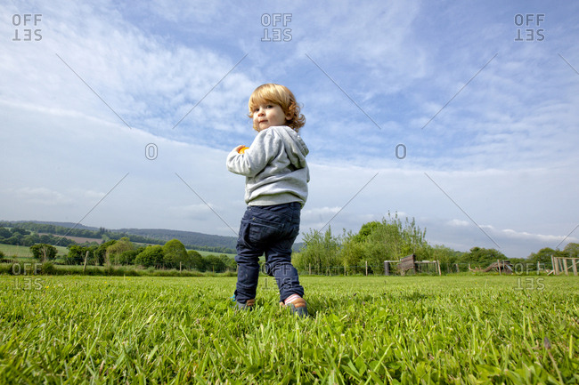 A little boy having fun on a green field in the country side, Caurel Brittany, France.