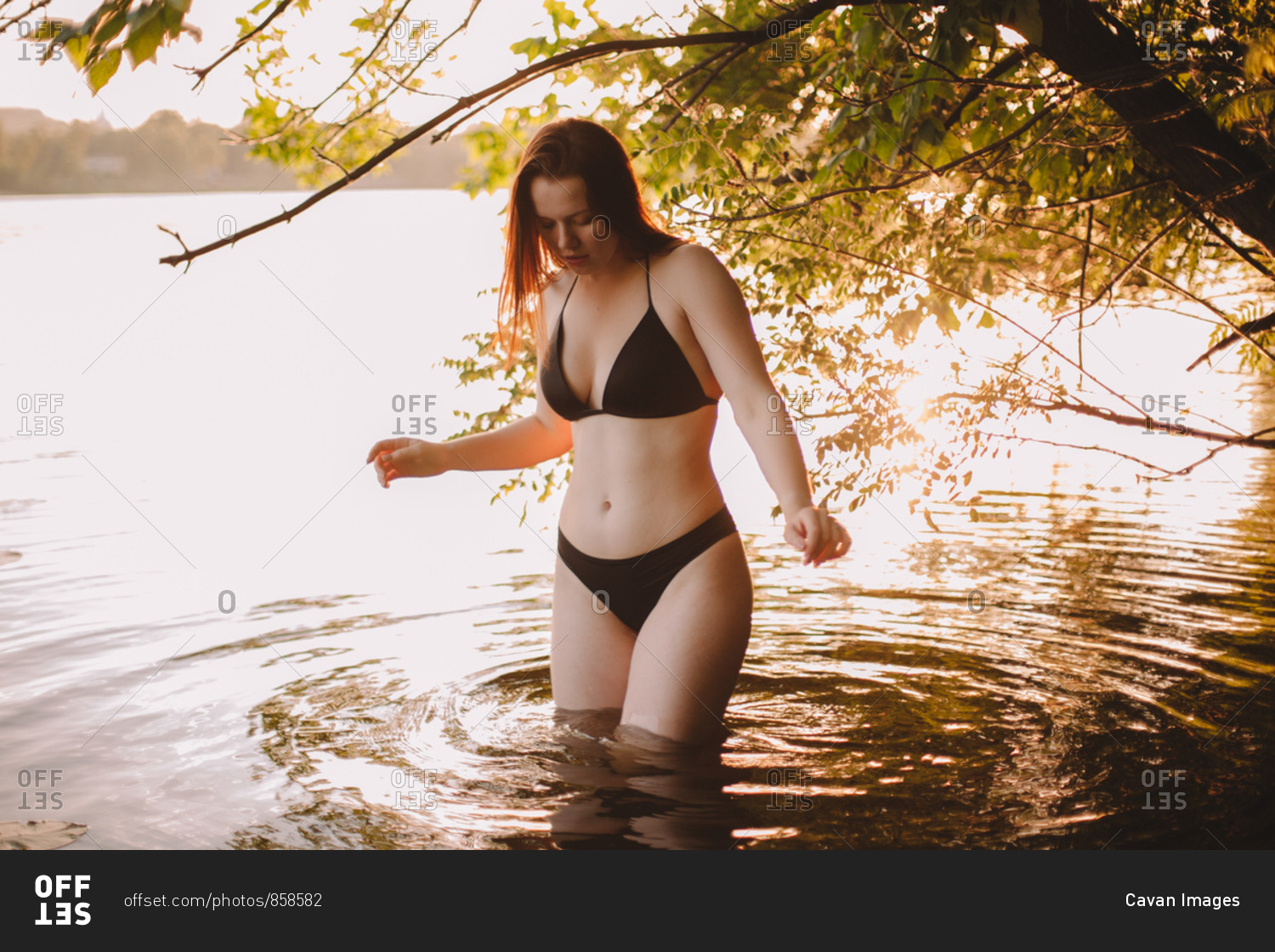 Teenager wearing swimwear standing in lake at forest stock photo